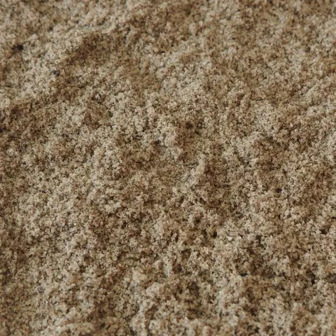 Grofkorrelig beige zand met donkere spikkels ertussen