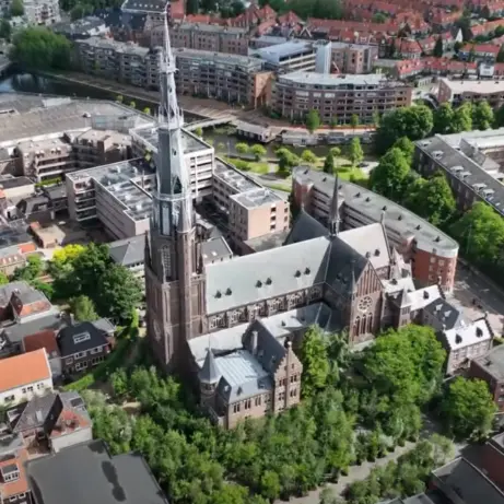 Luchtfoto van een binnenstad met een hoge kerktoren en grachten