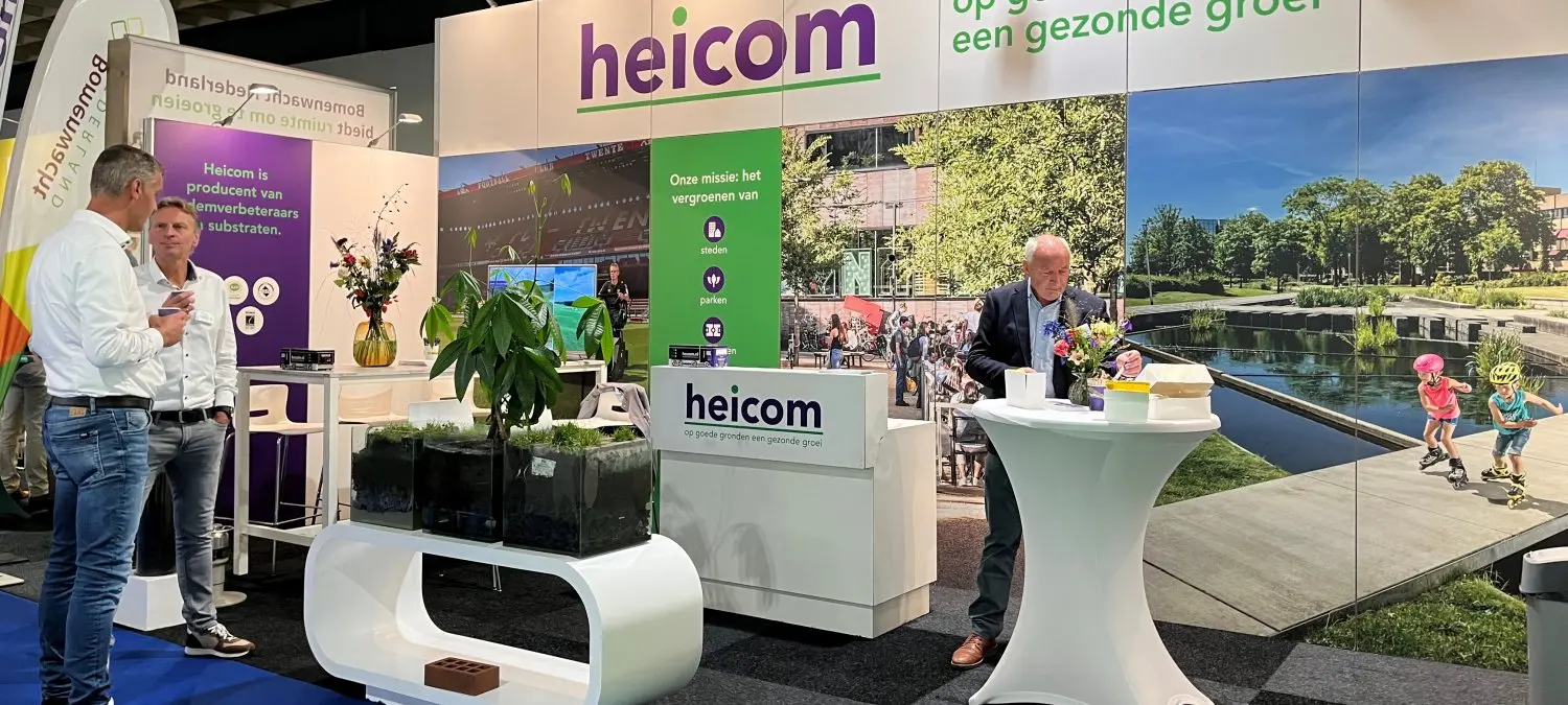 Man aan een statafel en bezoekers in gesprek op een beursstand