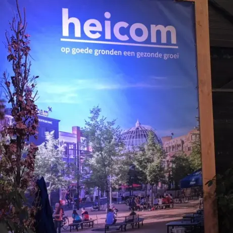 Verlicht Heicom-doek met stadsplein in een houten frame tussen planten
