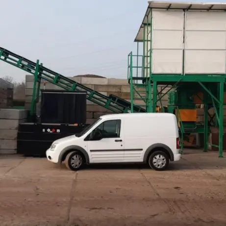 Paarse Heicom-vrachtwagen en bestelbus bij een zeefinstallatie op een bedrijfsterrein