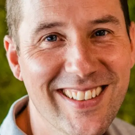 Portret van Joeri Faas lachend voor een groene moswand