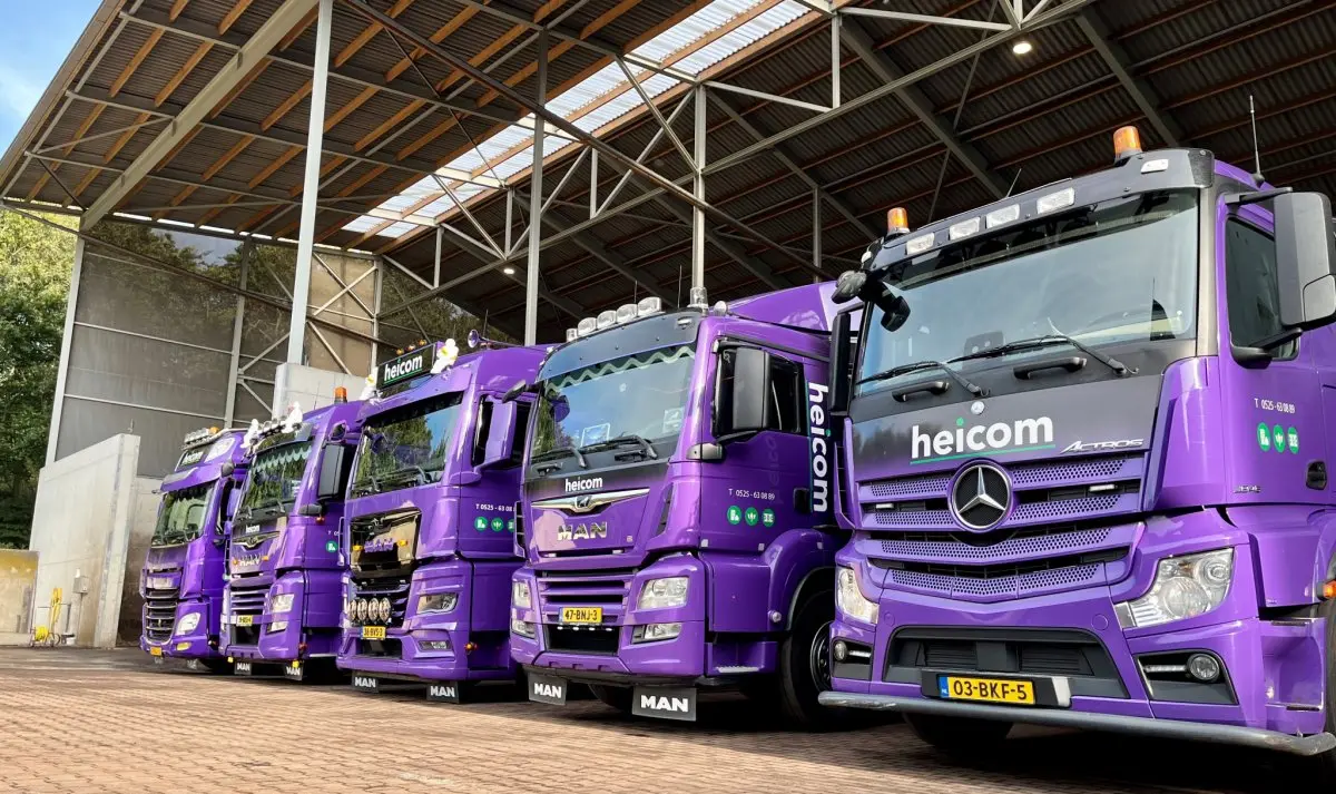 Rij paarse Heicom-vrachtwagens schuin naast elkaar onder een overkapping