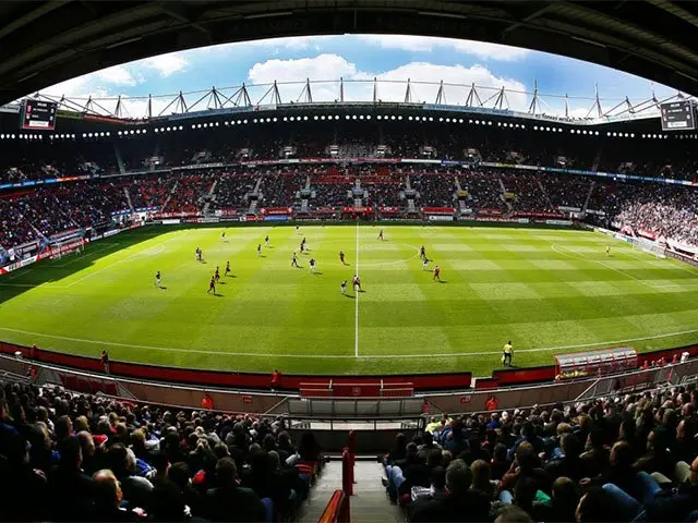 Voetbalstadion met volle tribunes en spelers op het grasveld