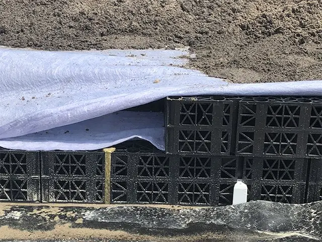 Zwarte waterbergingskratten afgedekt met wit doek in een zandbed