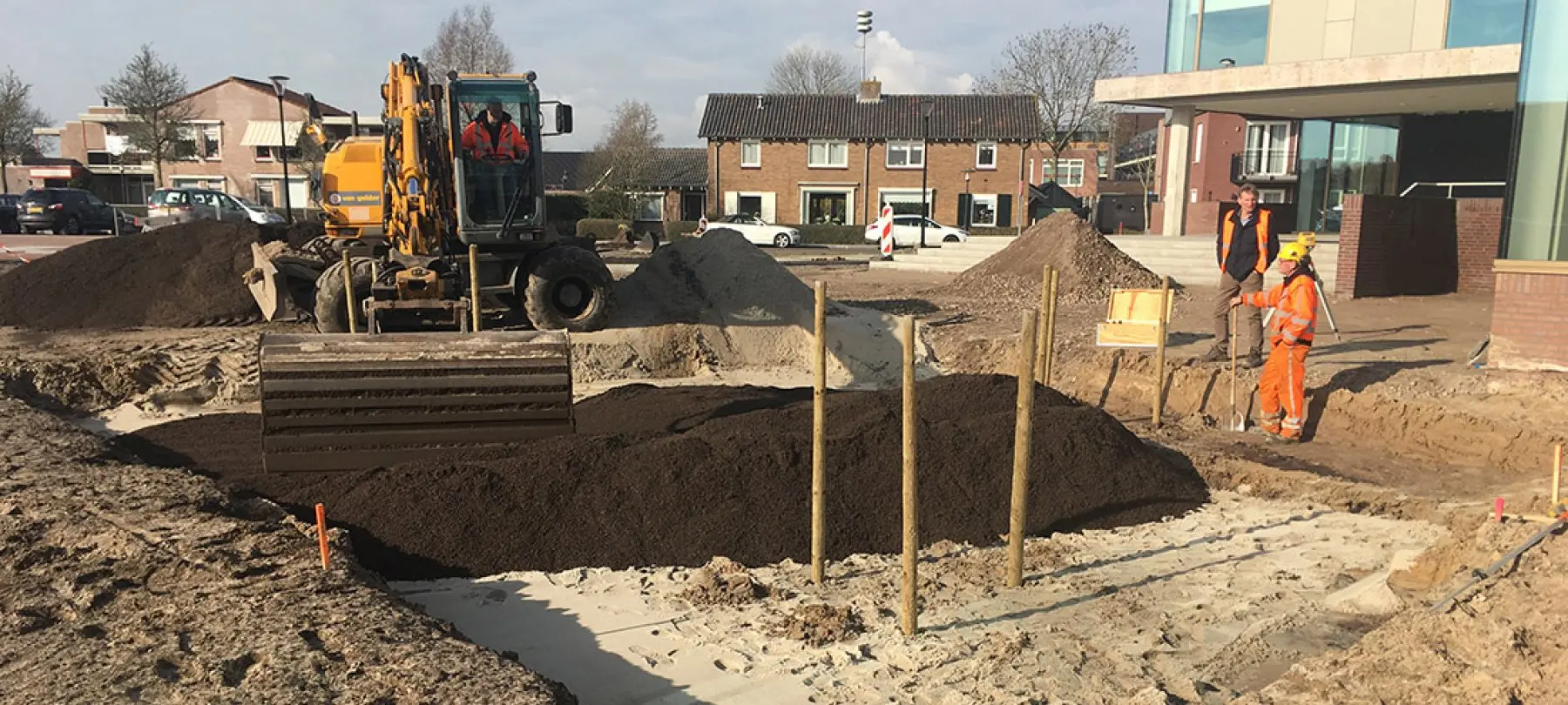 Graafmachine en werkmannen leggen een plantvak met donkere grond aan