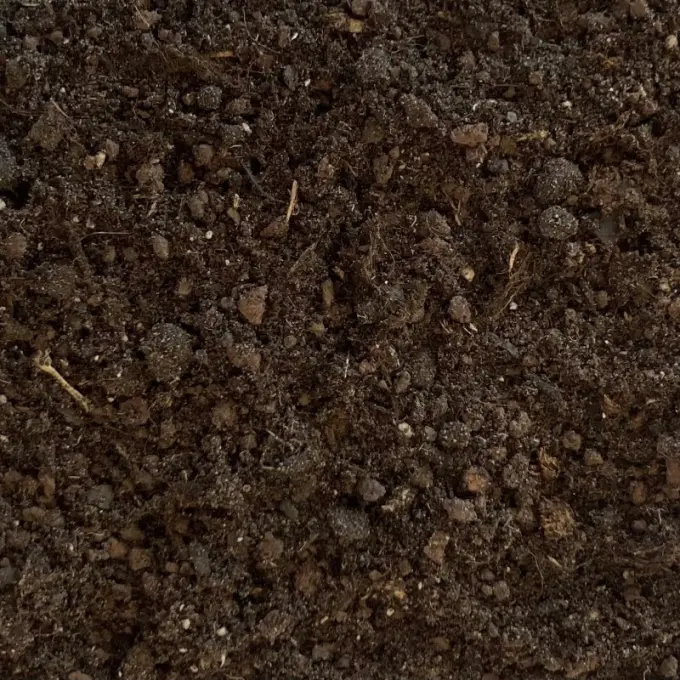 Bruin kruimelig substraat met plantenvezels en kluitjes van dichtbij
