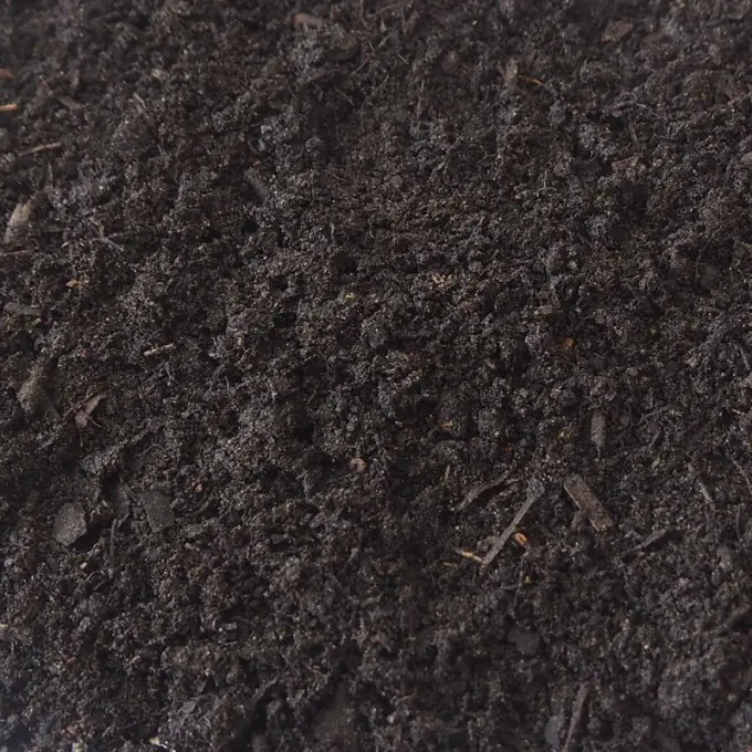 Donkerbruine compost met lichte houtvezels en kluitjes ertussen